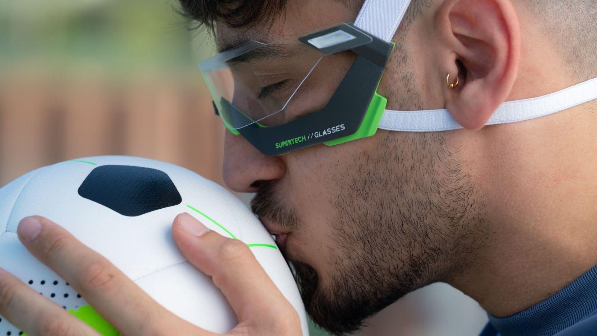 A soccer player wearing the Rayzor goggles, holding a ball close during a moment of focus.