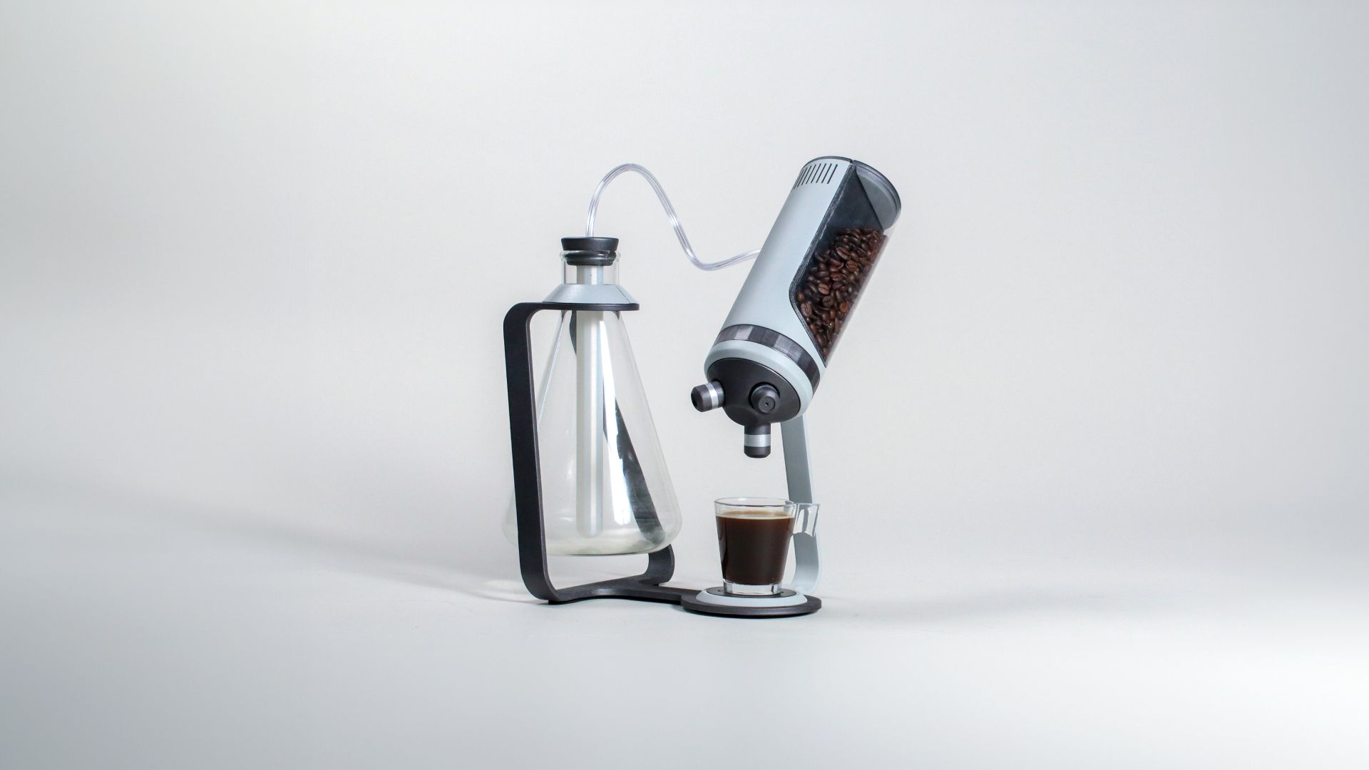 The Microcoffee brewer tilted, pouring into a small glass of espresso.