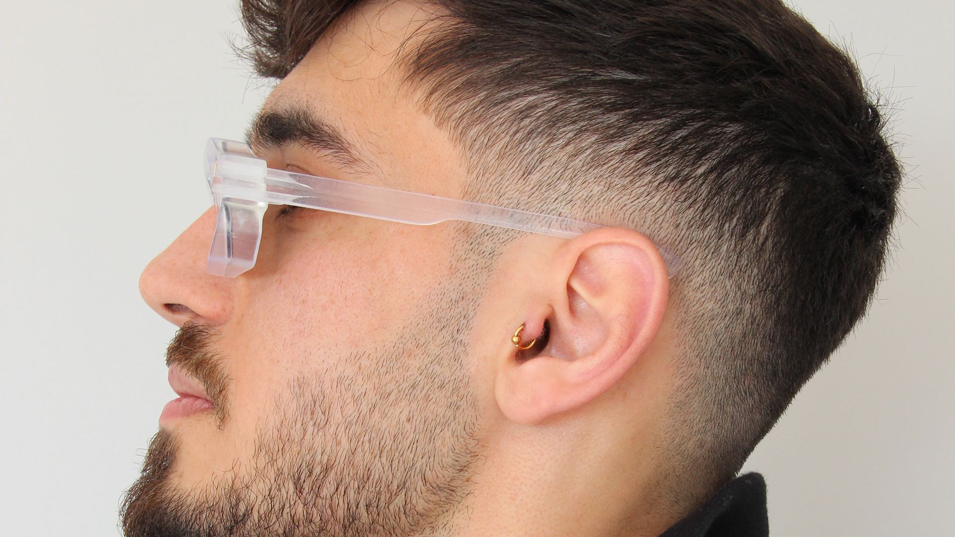 Side profile of a man wearing the clear Unfoldable frames, showing the temple and X-connector.